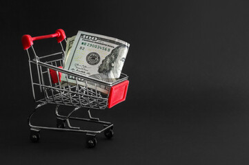 Shopping cart with money on black. Business concept.