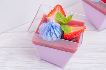 Panna cotta in a cup decorated with strawberries and blue marshmallows