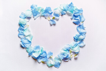Obraz premium 造花の青い花びらでかたどったハートのフレーム。白いコピースペース。平置きの俯瞰撮影。白バック。