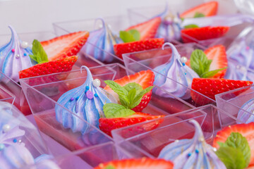 Panna cotta in a cup decorated with strawberries and blue marshmallows