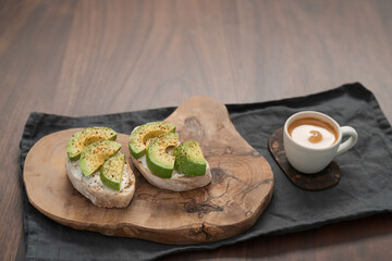 Avocado sandwiches with espresso for breakfast on walnut wood table