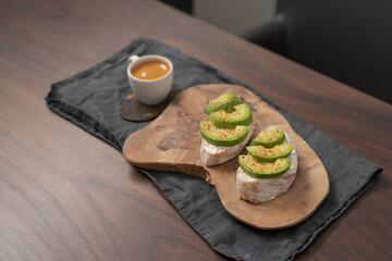 Avocado sandwiches with espresso for breakfast on walnut wood table