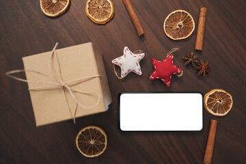 flat lay with smarthone and christmas decorations on walnut table