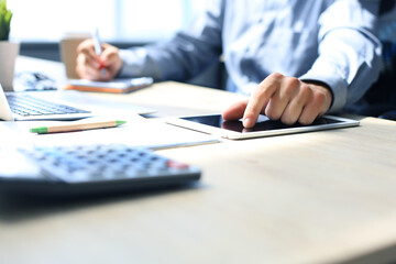 Fototapeta premium Young modern business man working using digital tablet while sitting in the office.