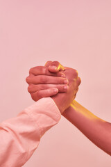 Family power. Close up of two men, brothers holding each other arm isolated over light pink background