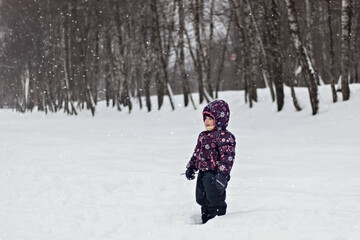 Fototapeta na wymiar A little girl stands in a winter snow Park. Christmas holidays