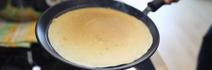 Hand holds pan with pancake, cooking at home. Available products, home recipes. Main types breakfast. Rules for working with toppings and assembly popular pies. Gluten free dough