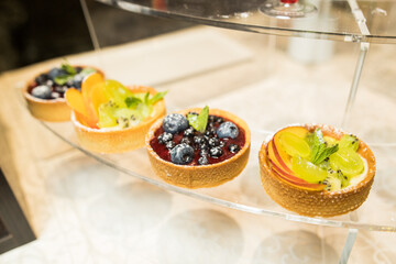 Four cheesecakes with fresh fruits on glass table