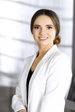 Portrait of a young successful businesswoman, while she is standing together with her colleague in a modern office. Concept of success in a business