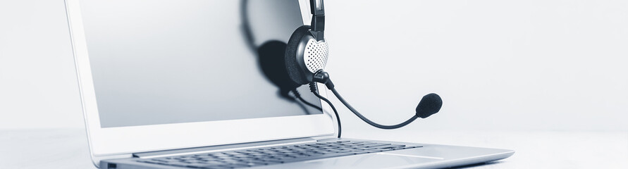 Laptop. Mockup screen and headphones on grey desk and plain background wide banner. Distant...