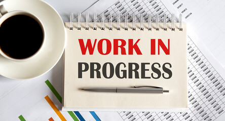 Notepad with the text Work in Progress on a light background, with coffee