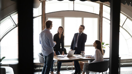 Funny briefing. Diverse multiethnic coworkers meeting on seminar at conference room, having fun laughing on working routine moment, joking in good mood glad to find best solution of problem discussed