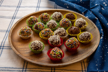 Christmas Truffles with Chocolate and Rum. Coated in coconut and sprinkles, handmade from scratch, in pretty colorful paper cups, on a decorated table.