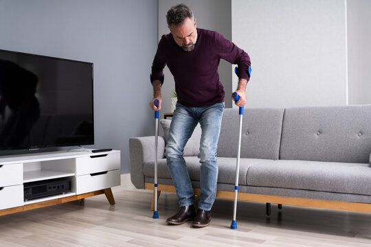 Elderly Man Using Crutches To Walk