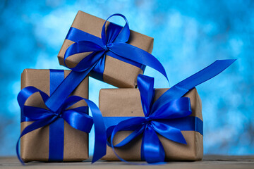 Christmas gift boxes with blue ribbons against blue lights garland and bokeh background. Holiday greeting card.