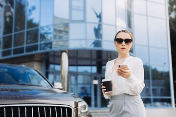 Fototapeta premium business woman drinking coffee and checking her phone on the way to work