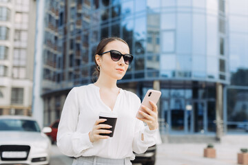 Business Woman Walking on the Street in the Business District, Checks Her Smartphone.