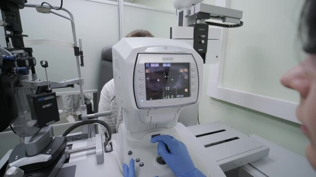 Woman doctor is viewing through ophthalmoscope in eyes of patient in ophthalmologic clinic. Professional inspection of vision