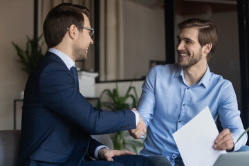 Good deal. Two business partners shaking hands after signing contract, client satisfied of getting...