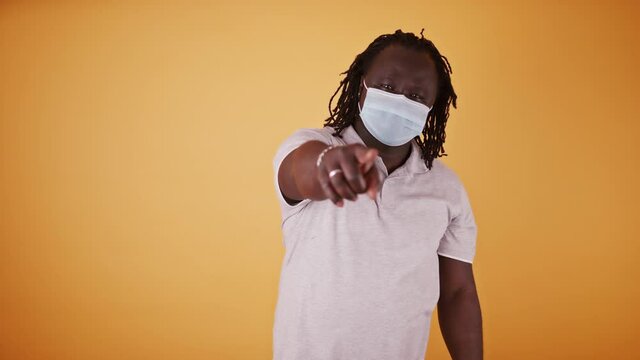 African american black man with medical mask and braidd hair pointing finget towards the camera. High quality 4k footage