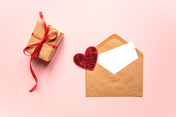 Creative Valentine Day romantic composition with paper envelope, red heart and gift box on pink background. Mockup with copy space for blogs and social media.