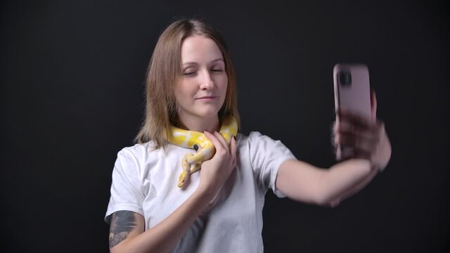 Slow motion shooting of woman with albino python, holding smartphone