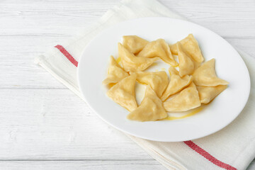 Russian dumplings on white plate on white wooden table