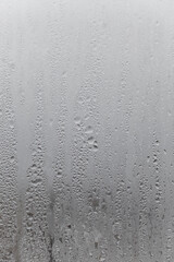 Close up water drop on grey background, misted glass with droplets of water draining down. Dripping Condensation