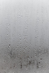 Close up water drop on grey background, misted glass with droplets of water draining down. Dripping Condensation