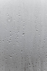 Close up water drop on grey background, misted glass with droplets of water draining down. Dripping Condensation