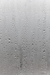 Close up water drop on grey background, misted glass with droplets of water draining down. Dripping Condensation