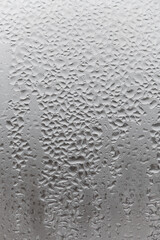 Close up water drop on grey background, misted glass with droplets of water draining down. Dripping Condensation