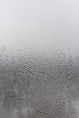 Close up water drop on grey background, misted glass with droplets of water draining down. Dripping Condensation