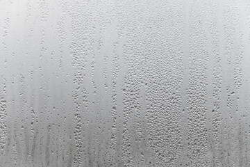 Natural drops of water flow down the glass, high humidity in the room, condensation on the glass window. Neutral colors. Excellent background with condensation drops texture