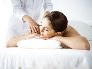 Beautiful brunette woman enjoying back massage comfortable and blissful. Spa and medicine concept