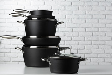 Set of cookware on table against white brick wall