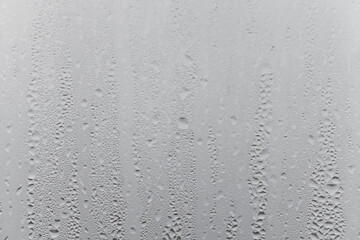 Close up water drop on grey background, misted glass with droplets of water draining down. Dripping Condensation