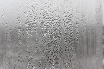 Close up water drop on grey background, misted glass with droplets of water draining down. Dripping Condensation