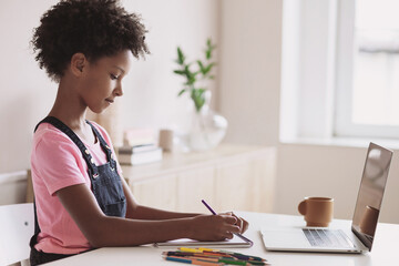 Cute little girl having lesson online at home. Kid drawing and using laptop. Online homeschooling, distance education, studying, technology, lockdown, e-learning, schoolgirl children lifestyle concept
