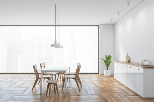 White and wooden dining room with window, light furniture on parquet floor
