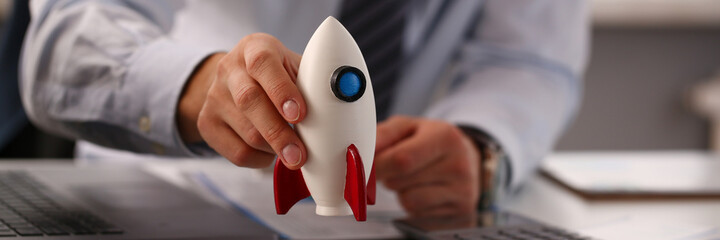 Close up of male hand that holding box in shape of rocket and going to count coins