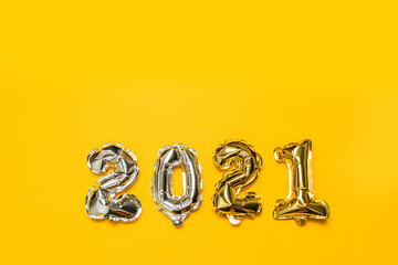 2021 golden foil balloons numbers with copy space on yellow background. New year and xmas holiday concept.