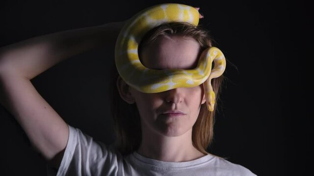 Slow motion video of woman with pet python albino crawling on her eyes
