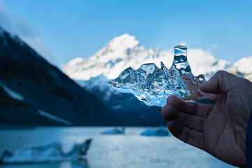 Tourist holding an ice against the mighty Mt Cook and iceberg-speckled Hooker lake