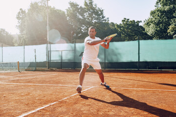 Fit man plays tennis on tennis field