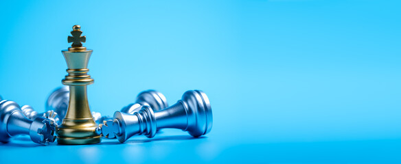 Golden king surrounded with chess pieces on sky blue background © thanmano