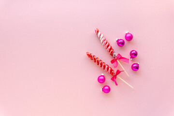 Two multicolored lollipops with balls on a pink background. Space for text