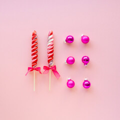 Two multicolored lollipops with balls on a pink background, top view