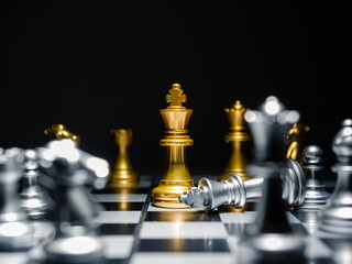 Golden king surrounded with chess pieces on chess board with dark background