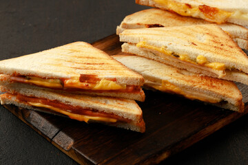 Assortment of toasted triangle sandwiches on wooden board